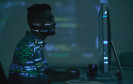 Mann sitzt vor Desktop mit Code-Projektion