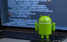 Android-Figur mit Code auf Comoputer-Bildschrim im Hintergrund