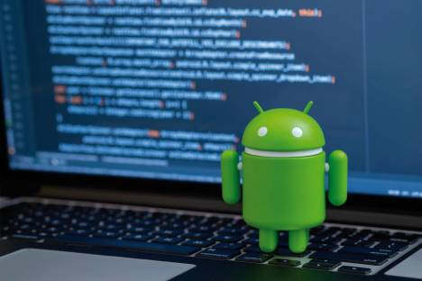 Ein Android-Roboter steht neben einem Notebook mit Quellcode
