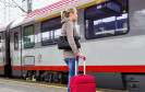 Frau vor Zug mit Koffer