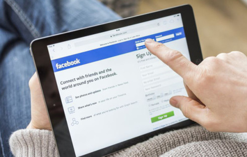 Person surft auf Facebook mit Tablet