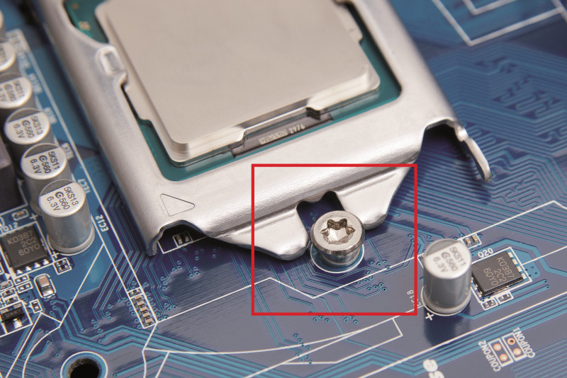 Rahmen fixieren: Der Metallrahmen muss unter diese Schraube rutschen, damit er die CPU sicher an ihrer Position fixiert.